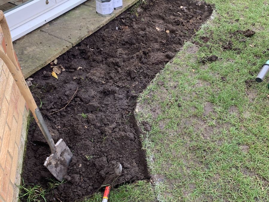 A newly dug garden border with turf lifted and soil turned over, a spade standing in the ground